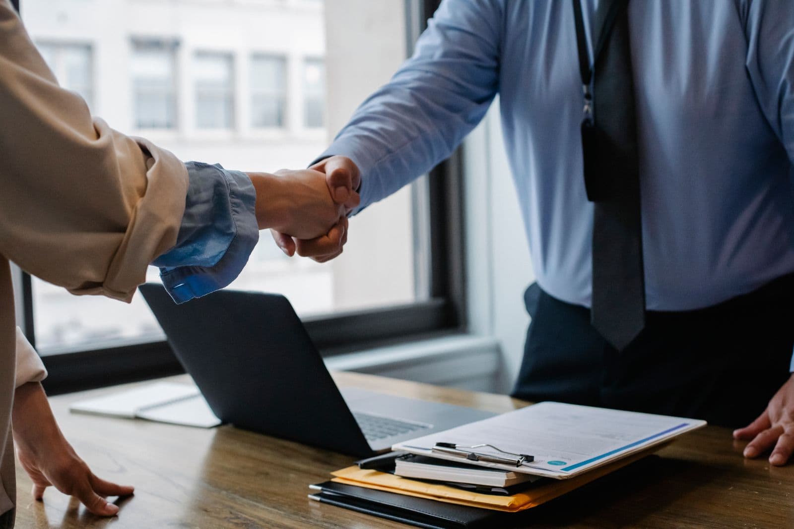 Buyer and seller shaking hands over a signed agreement